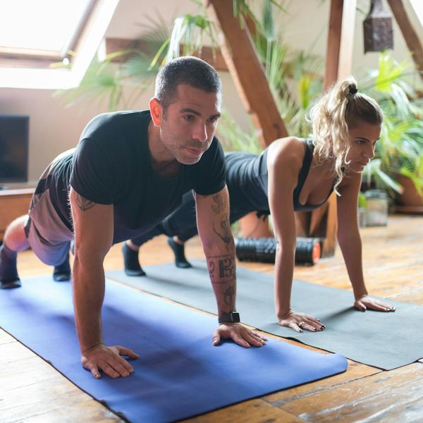 Man stretching on a yoga mat in a bright, sunlit room.
